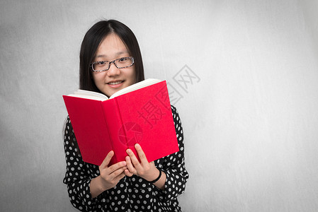 女孩在读一本红书女性优美青少年长发戏剧性分音大学学习肤色知识背景图片