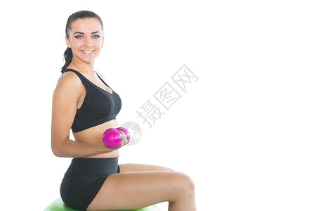 美丽的瘦瘦女人 用粉红色的哑铃坐在练球上背景图片