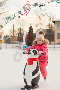 玩抽冰尜女孩可爱的小女孩在冰场滑冰女孩孩子女性数字溜冰场运动溜冰者手套套装生活方式背景