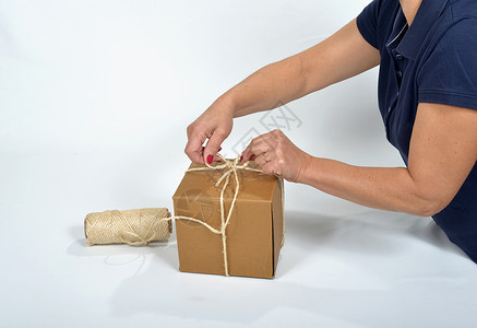 纸板包装一个年轻女人 用一串绳子领带蓝色女士细绳白色背景图片