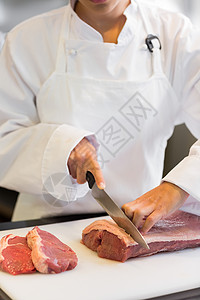 在厨房里切肉的手部中厨师烹饪职业混血女性餐厅切菜板食物工作柜台背景图片