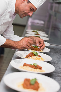 开心的厨师在意大利面盘上放叶餐厅制服职业烹饪工作酒店商业大楼男人盘子背景图片