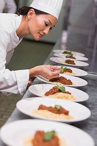 开心的厨师在意大利面盘上放叶晚餐餐饮白人烹饪职业女性餐厅商业台面厨房背景图片