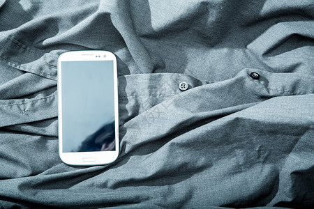 衬衫上的智能手机棉布男人屏幕展示套装衣柜技术商业软垫触摸屏背景图片