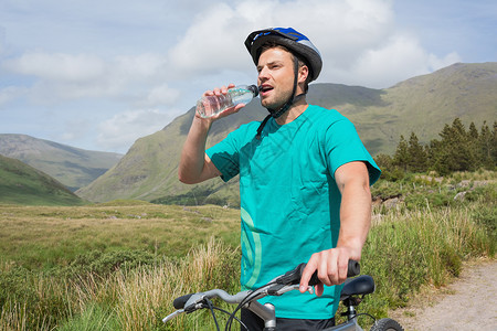 农村饮用水坐在山上骑着自行车喝饮用水的健身人背景