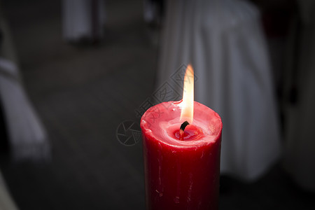 在黑暗中用橙色火焰燃烧的红蜡烛背景图片
