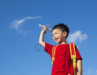 做飞机孩子小男孩拿着一个带背包的飞机玩具幼儿园太阳自由孩子手指喜悦天空幸福乐趣季节背景