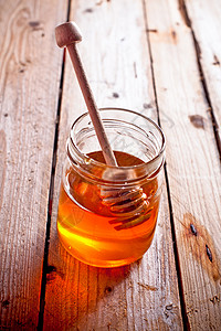满满的蜂罐和蜂棒食物生活植物产品勺子木头味道桌子芳香液体背景图片