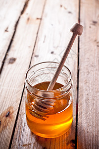 满满的蜂罐和蜂棒桌子味道勺子液体木头芳香营养乡村甜点植物背景图片
