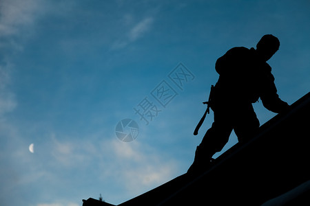 镬耳屋剪影在Silhouette的承包商在屋顶上工作职业工人男性建设者劳动装修建筑指甲月亮天空背景