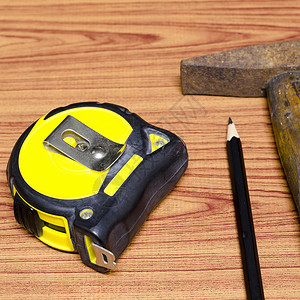 长度单位锤子胶带和铅笔指甲工作硬件黄色单位反射木工构造锤子磁带背景