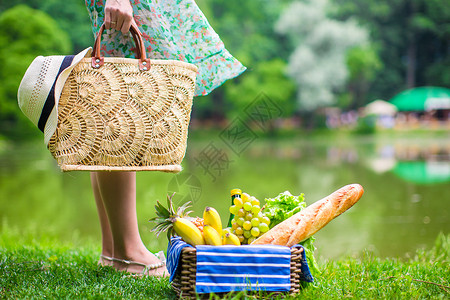 草方格配有水果 面包和草袋上帽子的彩礼篮子蓝色食物场地晴天稻草地毯方格草帽草原草地背景