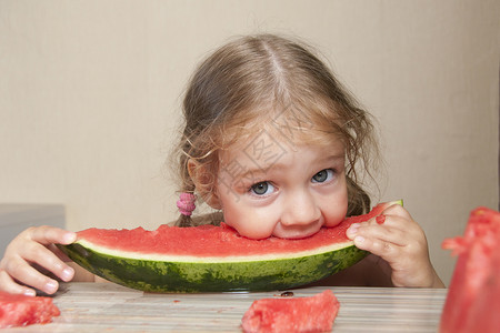 两岁女孩吃西瓜 面脸开心的两岁女孩食物面孔孩子厨房乐趣桌子背景图片
