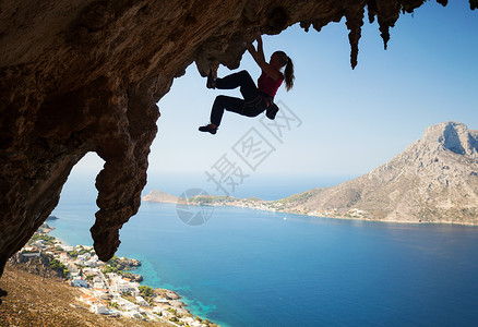 月光下登山者女孩在悬崖上攀岩的年轻女性月光天空风景女士岩石绳索高度运动登山者成功蓝色背景