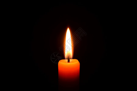 蜡烛火焰在黑色背景上点燃橙色蜡烛温泉黄色场景假期纪念馆宏观橙子宗教火焰烧伤背景