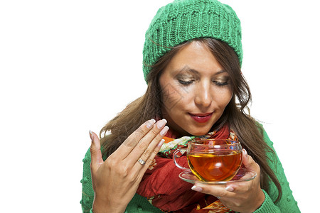 细细品味有魅力的女人 喝热茶暖和起来针织品绿色围巾女士帽子品味时尚玻璃杯子饮料背景