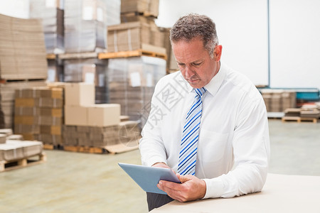 使用数字平板电脑的焦点老板仓库存货运输经理配送盒子船运工作职业男性背景图片