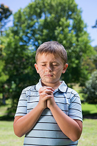 耶和华小男孩在祷告晴天绿地弟兄们闲暇双手眼睛微笑快乐见证人天主教徒背景