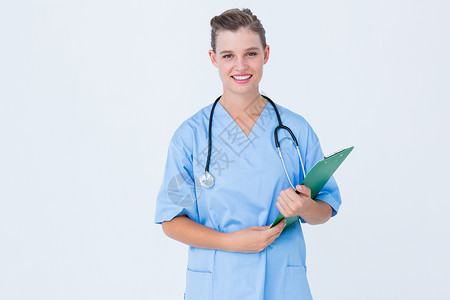 手持剪贴板的微笑护士制服写作蓝色专家医疗女性床单职业从业者磨砂膏背景图片