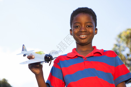 玩玩具飞机的小男孩儿公园微笑阳光黑色环境快乐农村男生童年飞行背景