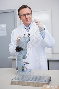 科学科学家检查幻灯片男人手套防护技术男性医学工作服实验研究显微镜背景图片