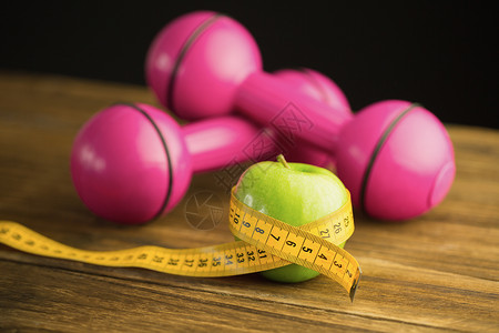 粉红哑铃 配有绿苹果和测量磁带绿色桌子减肥木头卷尺饮食健康饮食营养粉色瘦身背景图片