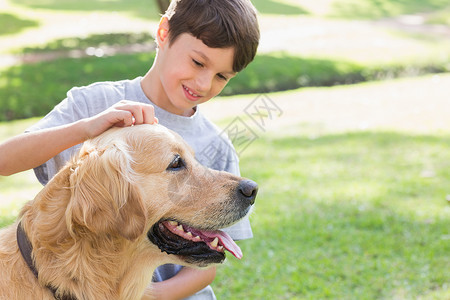 多猎犬小男孩和他的狗在公园里短发头发家畜草地微笑草原绿地拥抱棕色男性背景