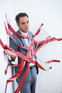 商务人士被繁琐的手续困住边界商业官僚公司磁带挑战套装商务男人红色背景图片