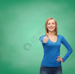 穿着便衣笑笑着的女孩露出大拇指木板学生衣服绿色黑板幸福蓝色成人课堂手势姿势高清图片素材