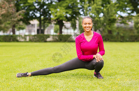 笑着的黑人女人在户外伸腿火车重量训练护理运动装微笑损失青少年身体运动背景