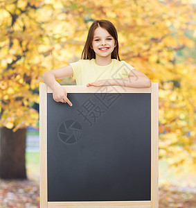 快乐的小女孩用手指对黑板学习青春期科学女孩孩子木板广告公园学校小学生背景图片
