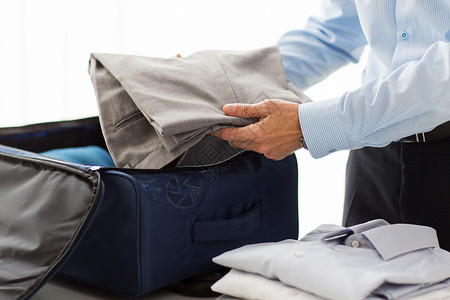 整齐地折叠桩商务人士将衣服包装在旅行袋中折叠衬衫准备房间裤子旅行行李男性工作人士背景