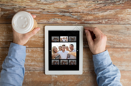 在平板电脑上贴有照片的男性手紧紧学生家庭饮料咖啡交友互联网屏幕工具男人画廊背景图片