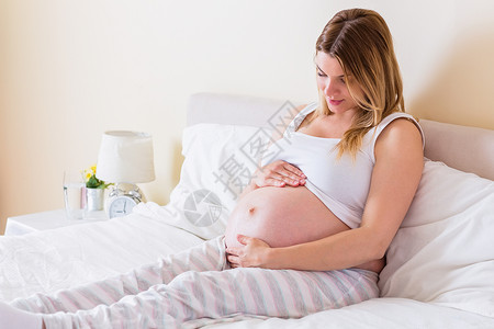 孕妇看着肚子 看她的肚子怀孕孕妇装女士腹部快乐女性休闲待产卧室服装背景图片