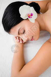 日间温泉漂亮的黑发美女 享受着花朵的按摩按摩师奢华女性生活方式水疗假期中心微笑呵护疗法背景