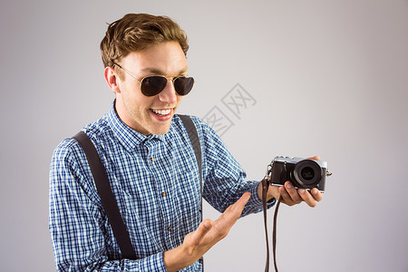 带着一台反光相机的傻笑嬉皮士复兴吊带裤快乐极客男性眼镜衬衫拍照男人格纹背景图片