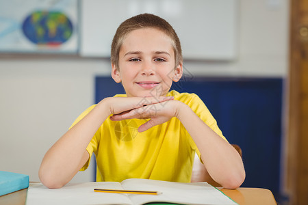 在课堂上坐在书桌边的微笑的学生学习男性教育学校班级早教瞳孔桌子幼儿园铅笔背景图片