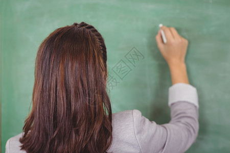 粉笔的头发教师在教室黑板上写作的近视职业粉笔班级记事本知识教育女性教学头发女士背景