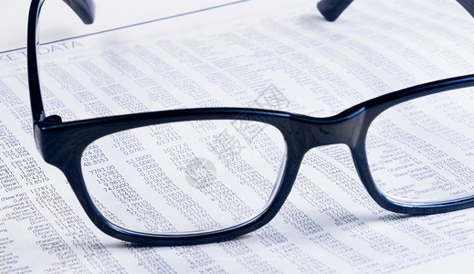 商业金融报纸报道看透眼镜镜片 商务人士的工作场所生长利润交易兴趣图表危机统计商务市场投资背景图片
