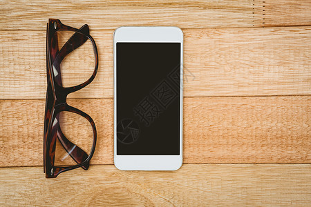 眼镜和智能手机视图触摸屏时尚白色木头桌子技术电话屏幕背景图片