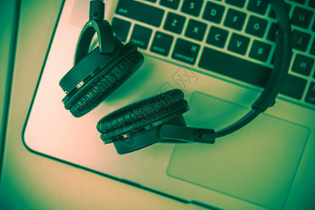 耳机和笔记本电脑扬声器互联网工作喇叭键盘绿色音乐家水平蓝牙技术背景图片