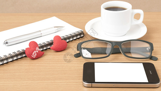 咖啡 电话 眼镜 笔记和心脏杯子红色桌子办公室手机背景图片