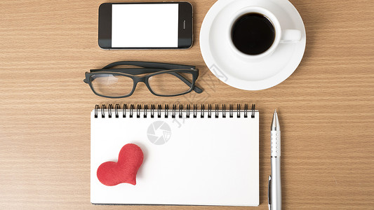 咖啡 电话 眼镜 笔记和心脏红色桌子手机办公室杯子背景图片