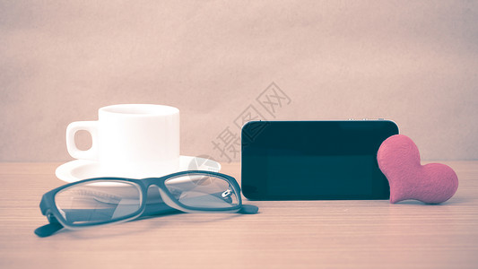 咖啡 电话 眼镜和心脏桌子木头手机白色红色杯子办公室背景图片