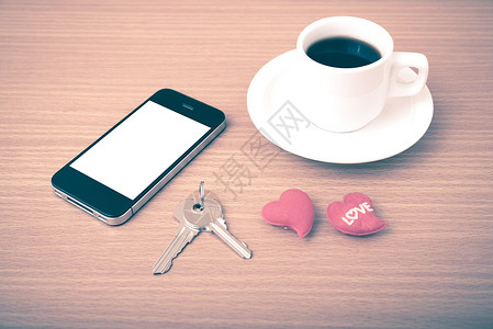 咖啡电话钥匙和心脏办公室桌子手机木头红色杯子礼物白色背景图片