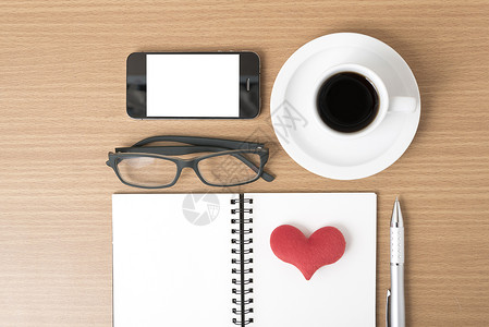 咖啡 电话 眼镜 笔记和心脏杯子桌子手机红色办公室背景图片