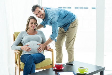 怀孕妇女肚子饿肚子的男子保健分娩喜悦公寓桌子服装家庭生活微笑椅子孕产背景