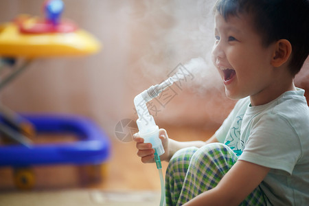 小男孩在家里吸气 给支气管服药 通过管子呼出蒸汽高清图片
