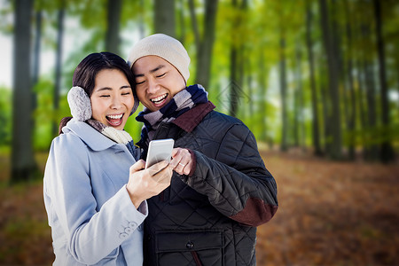 综保区看智能电话的一对快乐情侣 综合图像组合手机服装叶子活动建筑地面天空保暖休闲树木背景