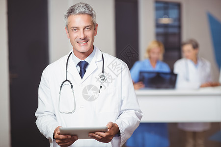 医院带字素材带着数字平板电脑的微笑的高级医生肖像背景